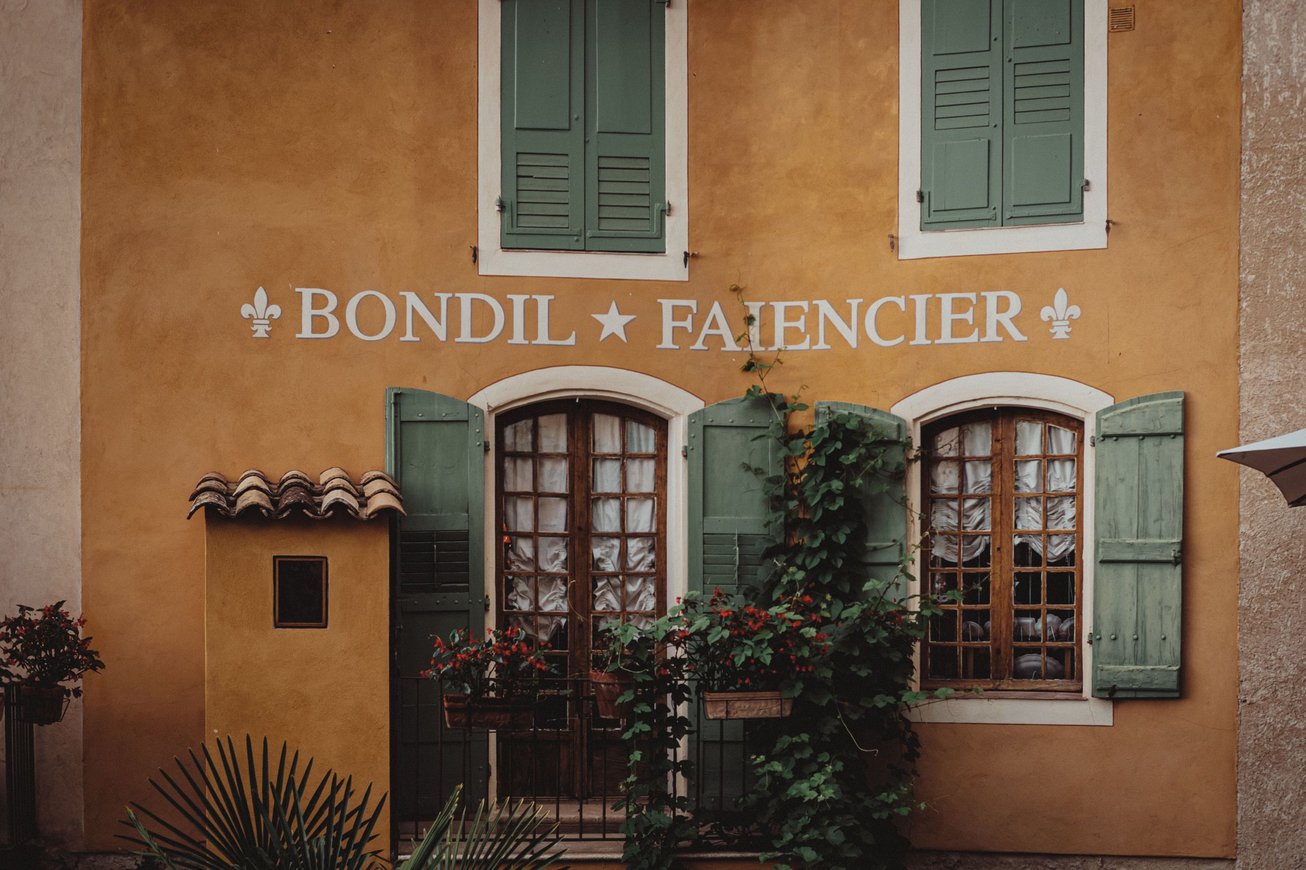 Façade provençale ocre avec volets et plantes